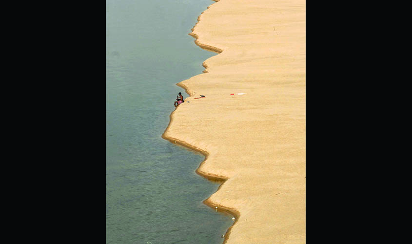 A villager takes a bath in partially dried-up Mahanadi river