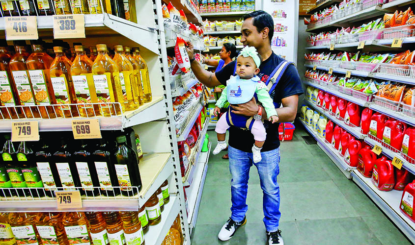 A customer carries his daughter as he buys goods at a store inside a shopping mall in Kolkata