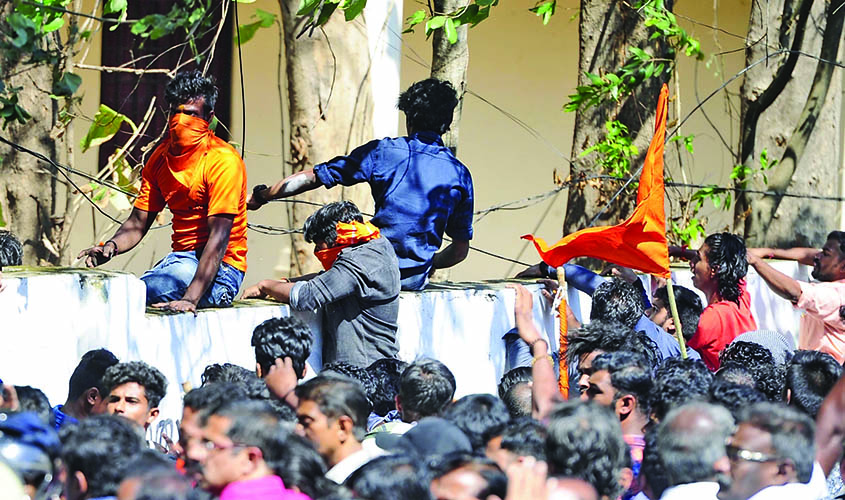 Palakkad: BJP workers jump a boundary wall during clashes with police during a protest amid a dawn-to-dusk Kerala shutdown called to denounce the visit of two women to the Sabarimala temple, that saw major violence, in Kerala's Palakkad on Jan 3, 2019. (P