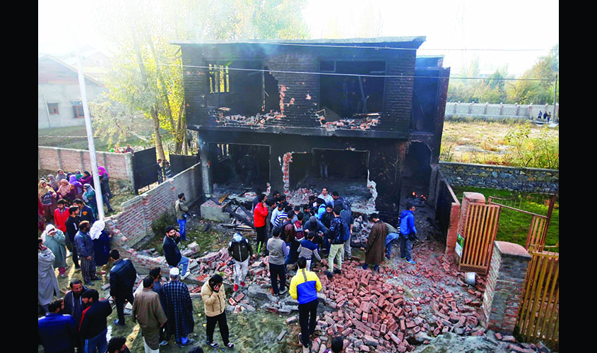 People inspect a house which according to local media was damaged in a gun battle between Indian security forces and suspected militants in Nowgam