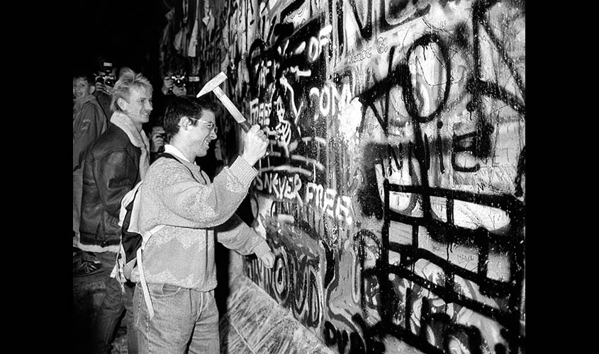 A MAN HAMMERS THE BERLIN WALL FILE PHOTO.