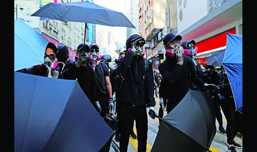 Anti-government protesters hold umbrella to take cover from tear gas during a march billed as a global