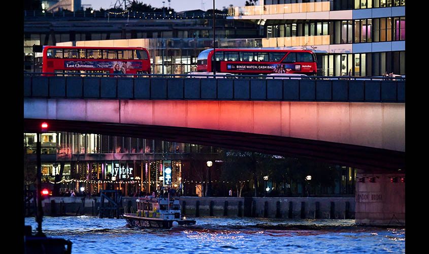 Police boat passes under as empty buses stand at London Bridge after an incident, in London