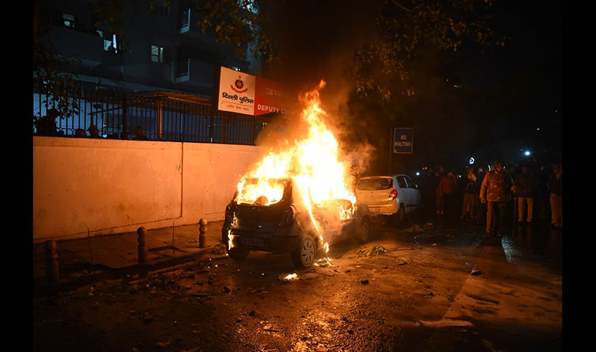 New Delhi: Police personnel douse fire after agitators turned violent and torched a car parked outside the DCP's office at Daryaganj during their demonstration against the Citizenship Amendment Act (CAA) 2019 and National Register of Citizens (NRC), in De