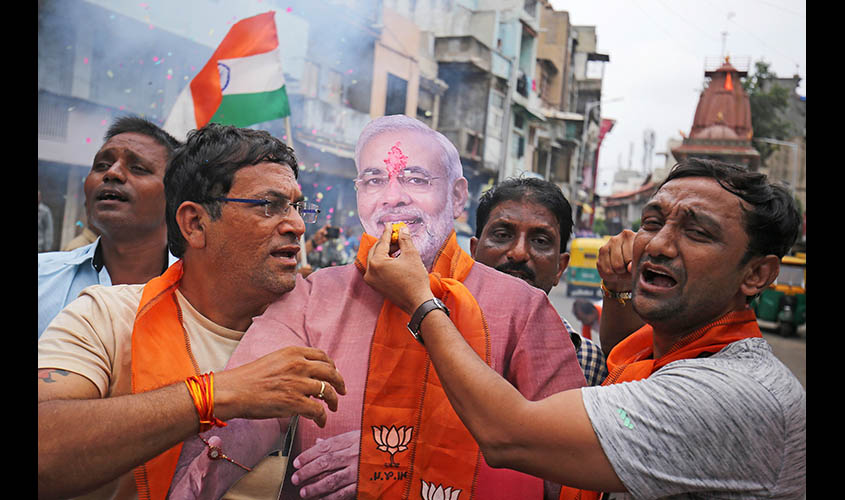 People hold a cut-out of India's Prime Minister Narendra Modi as they celebrate after the government scrapped the special status of Kashmir, in Ahmedabad