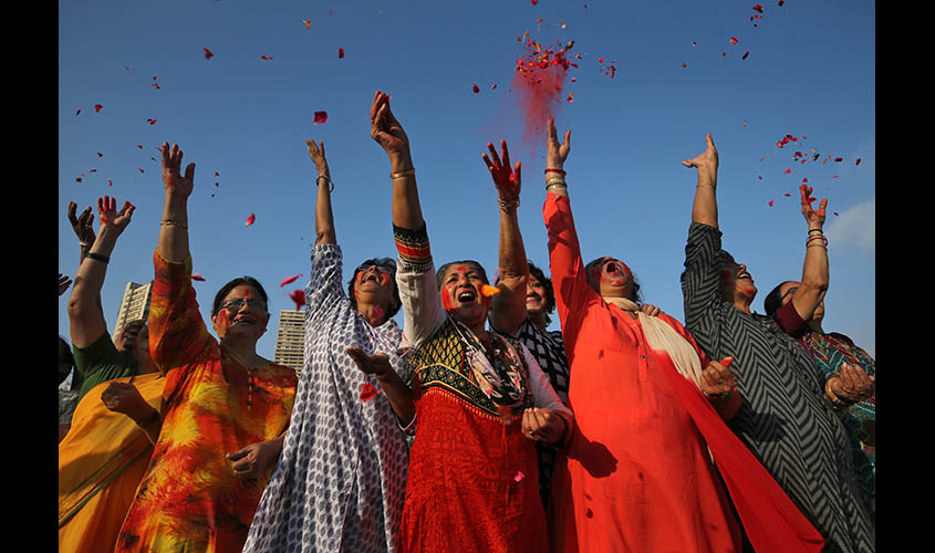 Women celebrate as they throw rose petals and coloured powder during the festival of†Holi in Mumbai