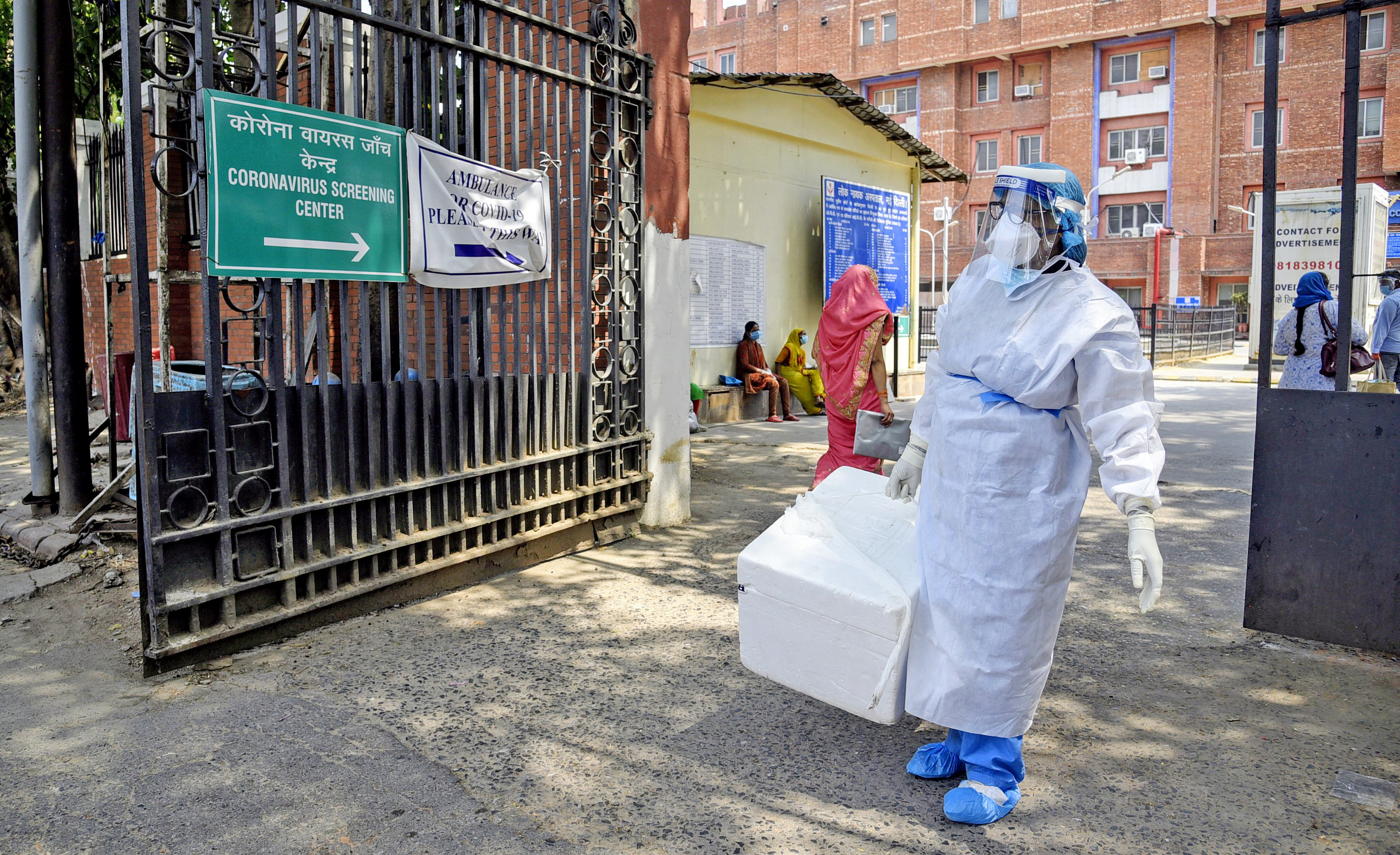 health staff worker wearing protective gears carries samples' box for the testing of COVID 19