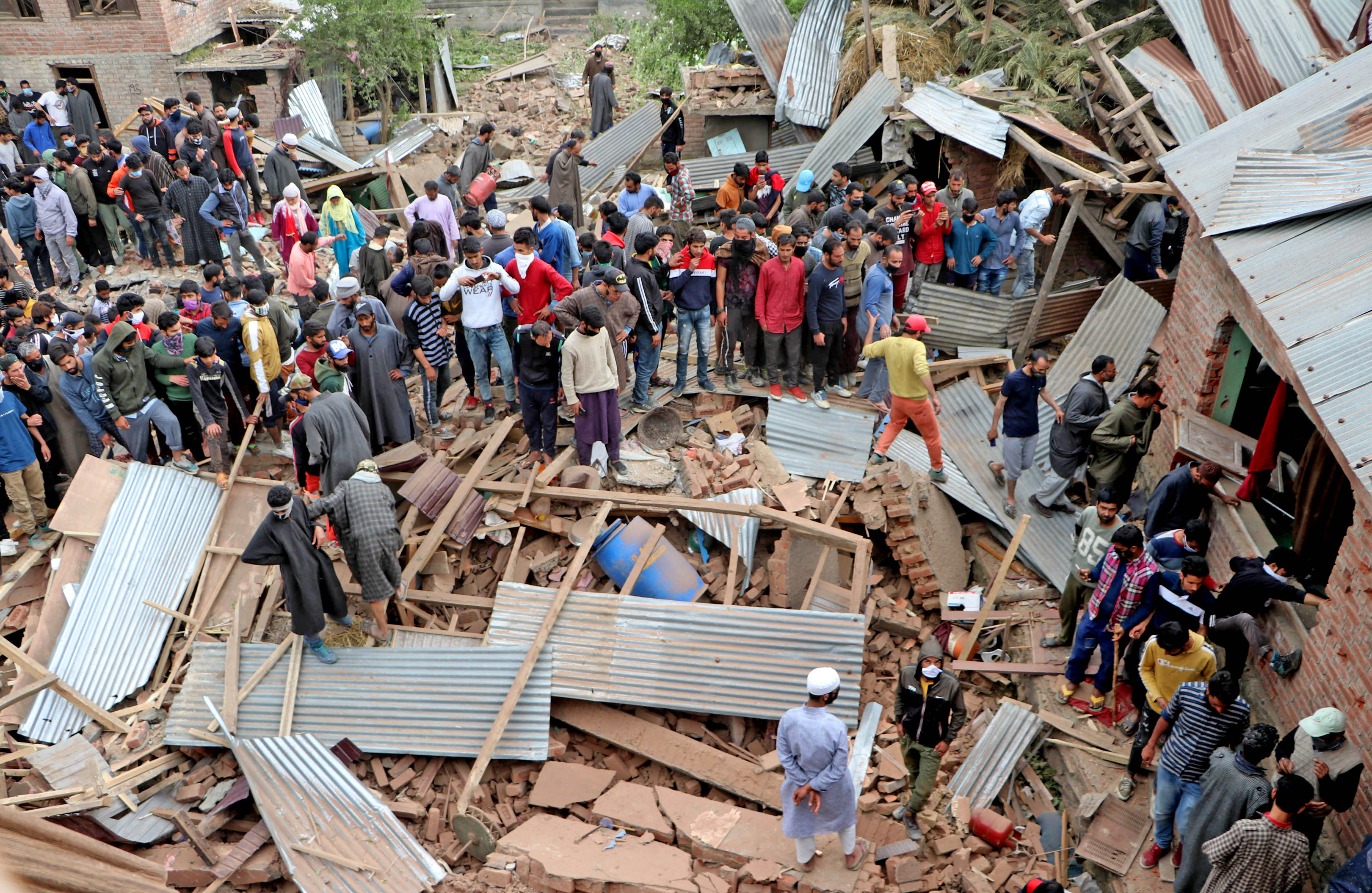 People look on the damaged house where Commander-in-Chief of Hizbul Mujahideen Riyaz Naikoo killed