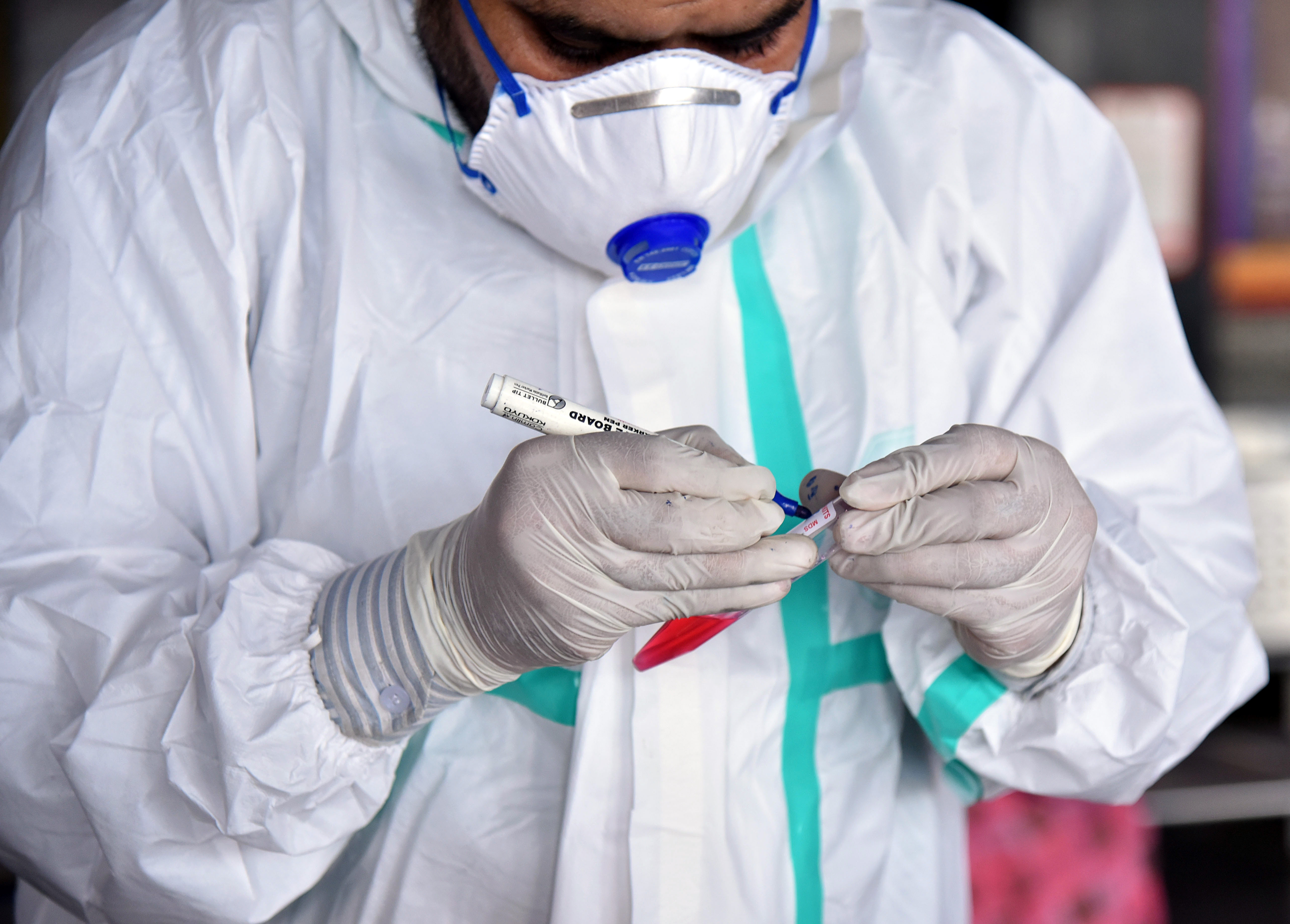 A health worker wearing a PPE kit marks the swab sample of the people collected for the COVID-19 test