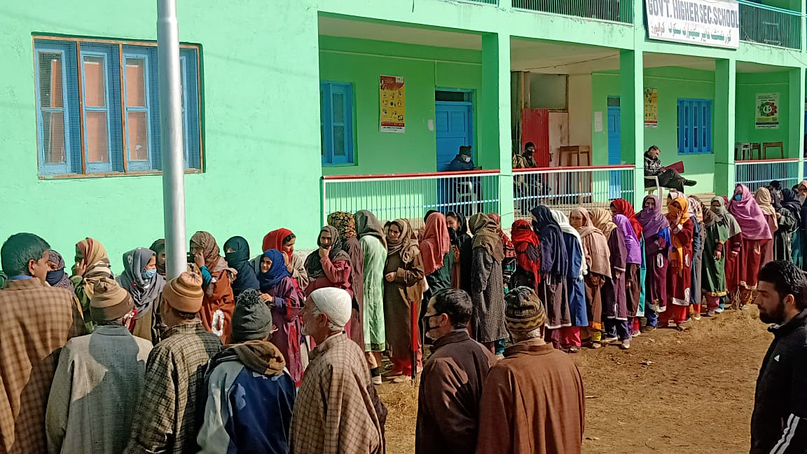 Voters stand in a queue to cast their votes as polling in the first phase of