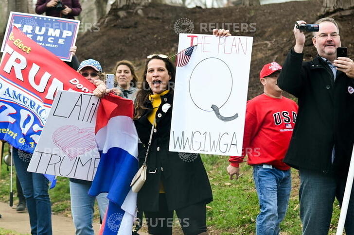 A supporter of U.S. President Donald Trump holds a sign referencing the QAnon conspiracy theory outside the Trump National Golf Club