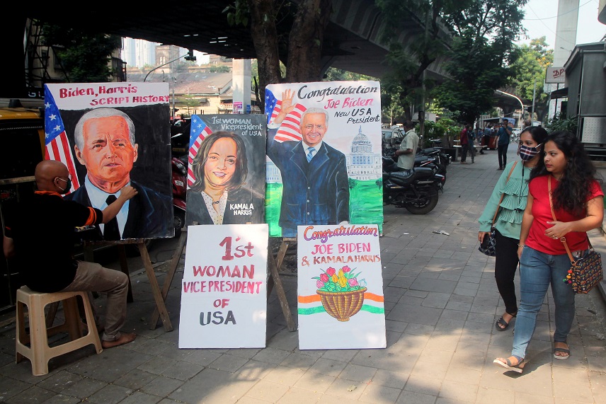 People walk past paintings depicting newly elected US President Joe Biden and Vice President Kamala Harris