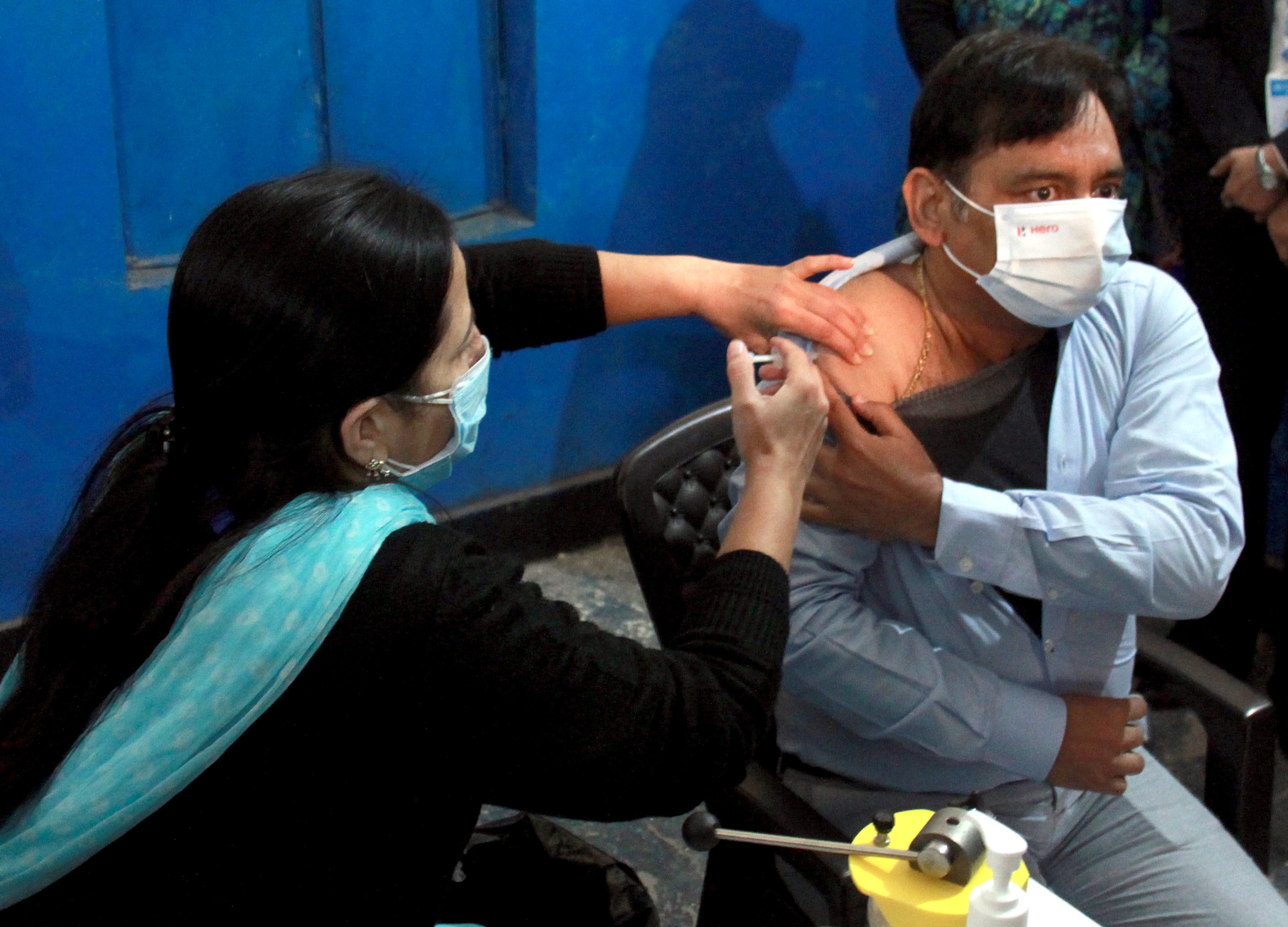 A medic administers the first dose of the COVID-19 vaccine to a frontline worker