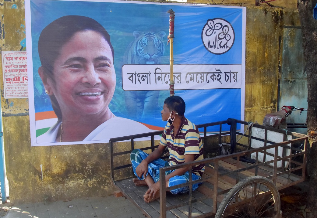 A person sitting on a rickshaw looks at the photo of West Bengal Chief Minister Mamata Banerjee