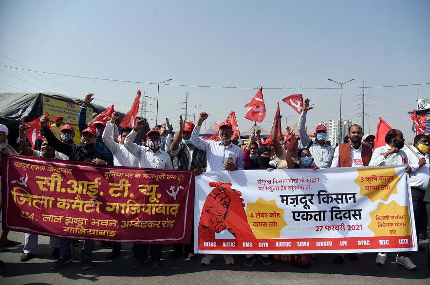 Farmers hold banners and raise slogans during a protest