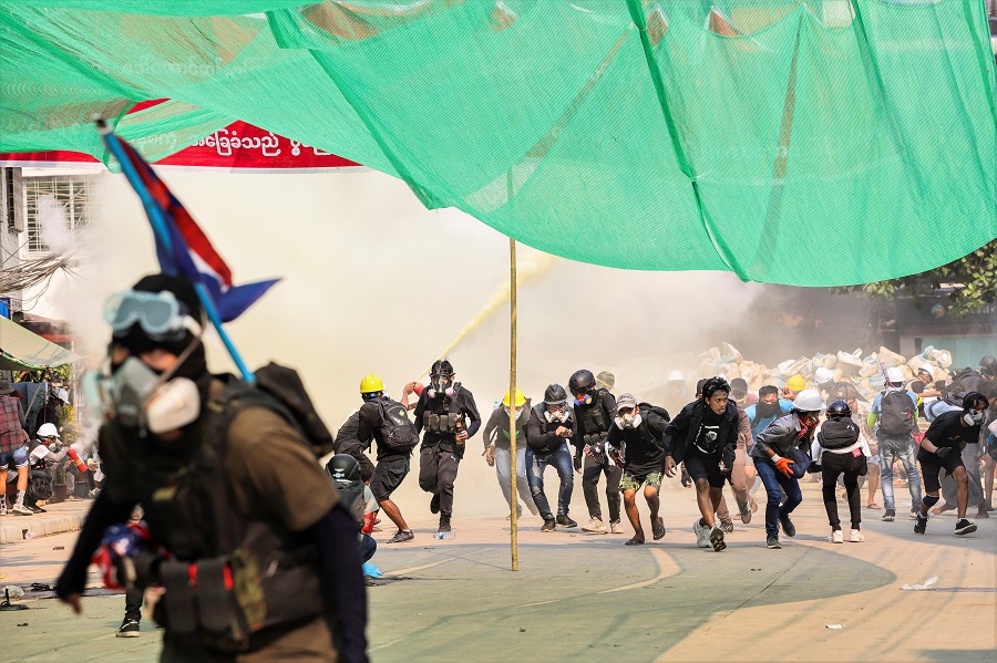 Protesters run during a crackdown of an anti-coup protests at Hlaing Township in Yangon, Myanmar