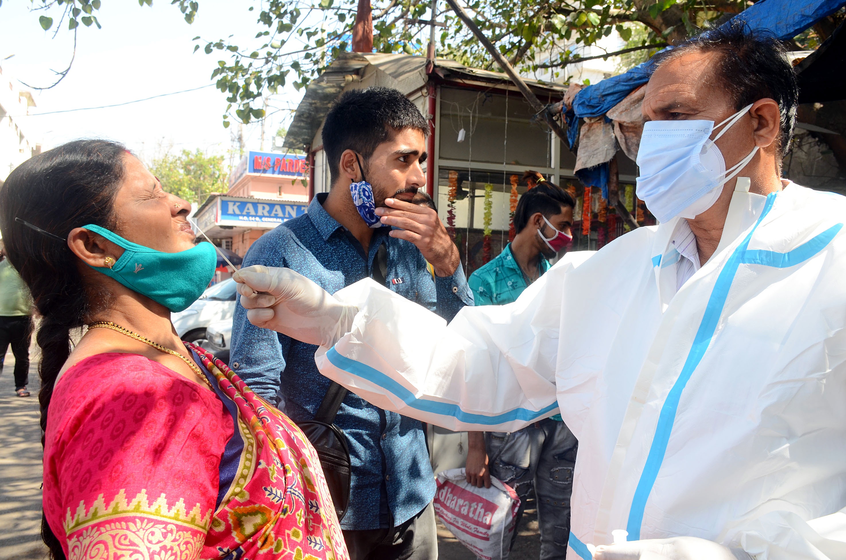 A medic collects a nasal sample of a passenger for the COVID-19 testing