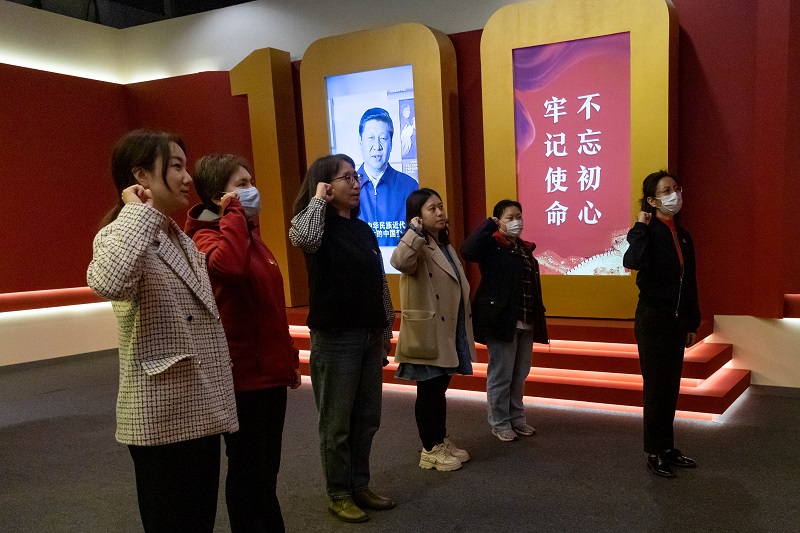 People swear an oath to the Chinese Communist Party (CCP) in front of an installation that includes an image of Chinese President Xi Jinping at an exhibition marking the party's 100th founding anniversary in Beijing