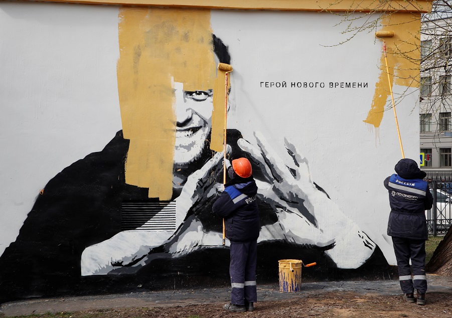 Workers paint over a graffiti depicting Alexei Navalny in Saint Petersburg