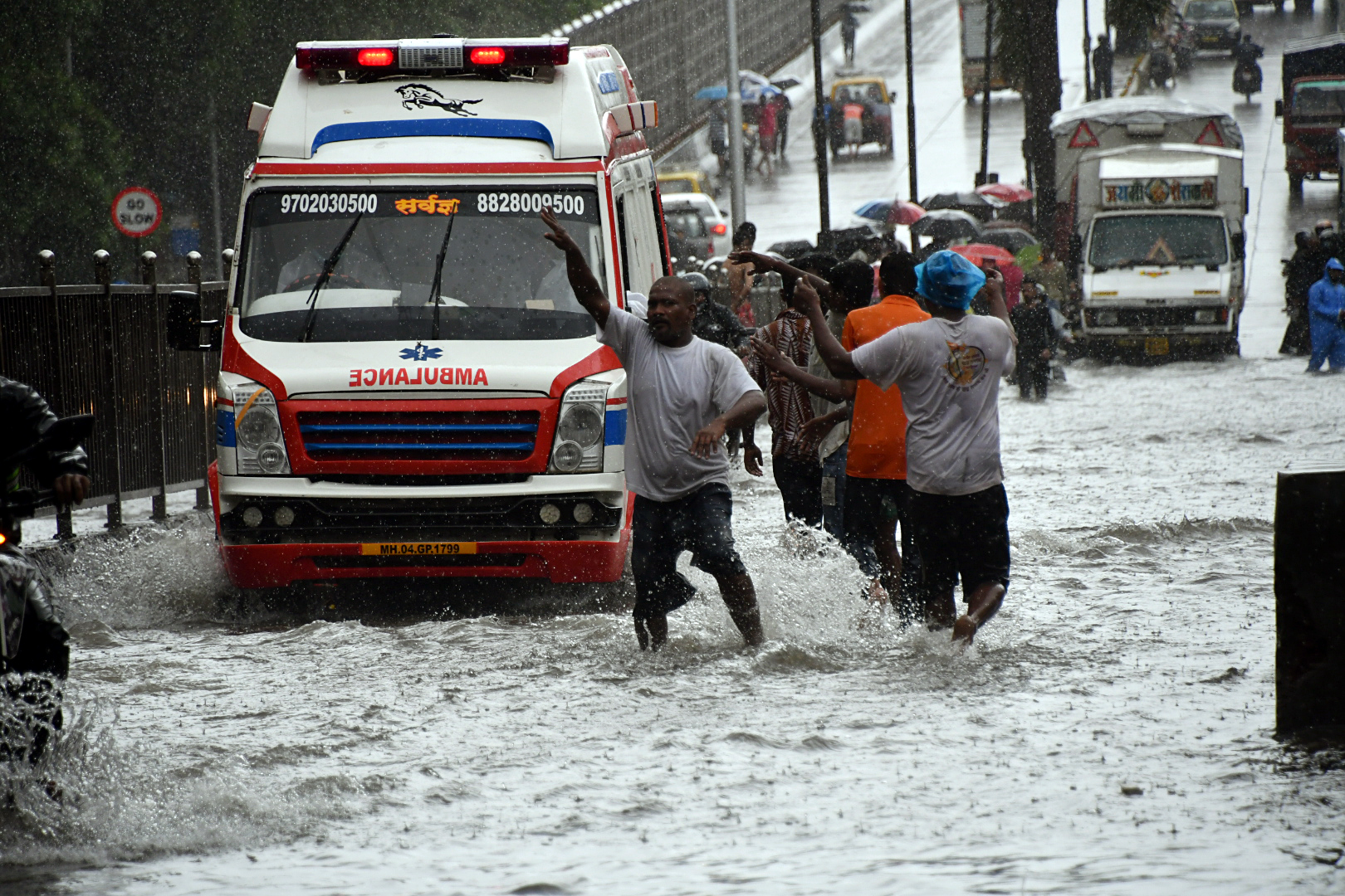 People make way for an ambulance through waterlogged roads during heavy rainfall