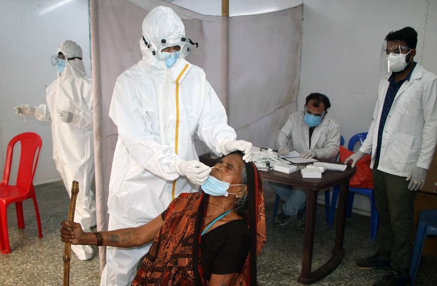 A healthcare worker collects the swab sample of a woman for COVID-19 testing