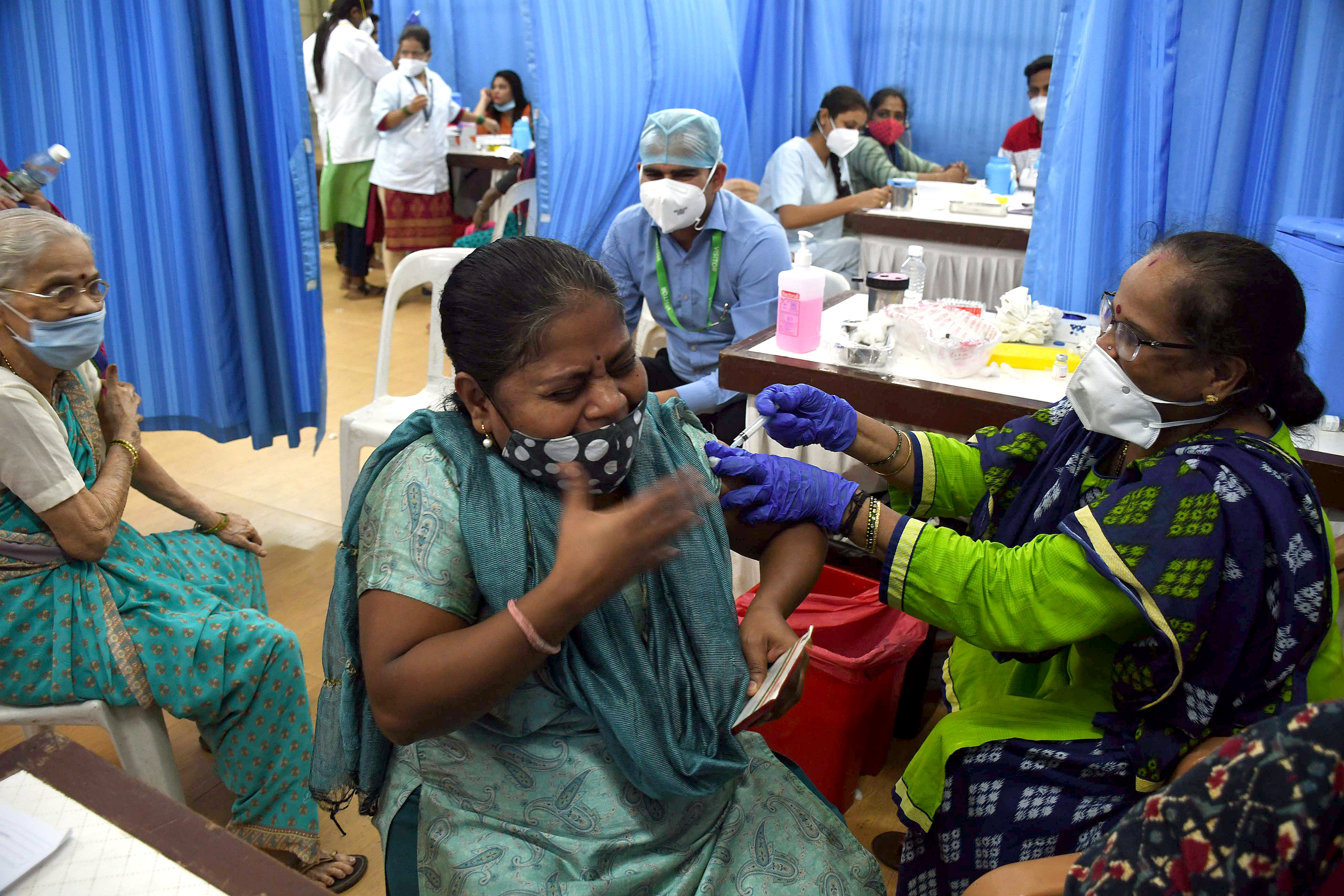 A beneficiary reacts as she receives a dose of the COVID-19 vaccine