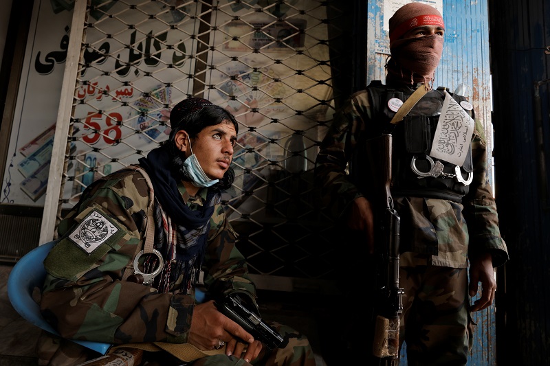 Taliban soldiers Omar Haqan and Jabir from Ghazni stand at the entrance of the currency exchange market in Kabul