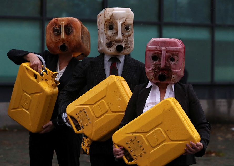 Ocean Rebellion activists wear oil canister masks as they spill fake oil in front of the venue for COP26 in Glasgow