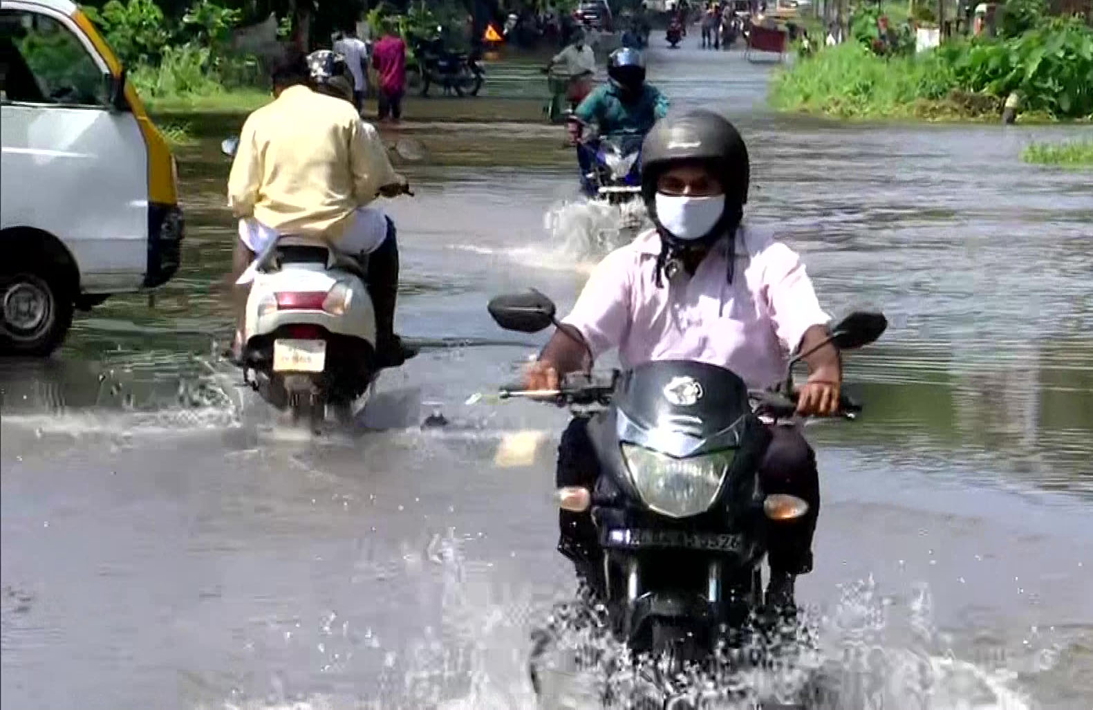 Commuters move through a waterlogged road following heavy rainfall