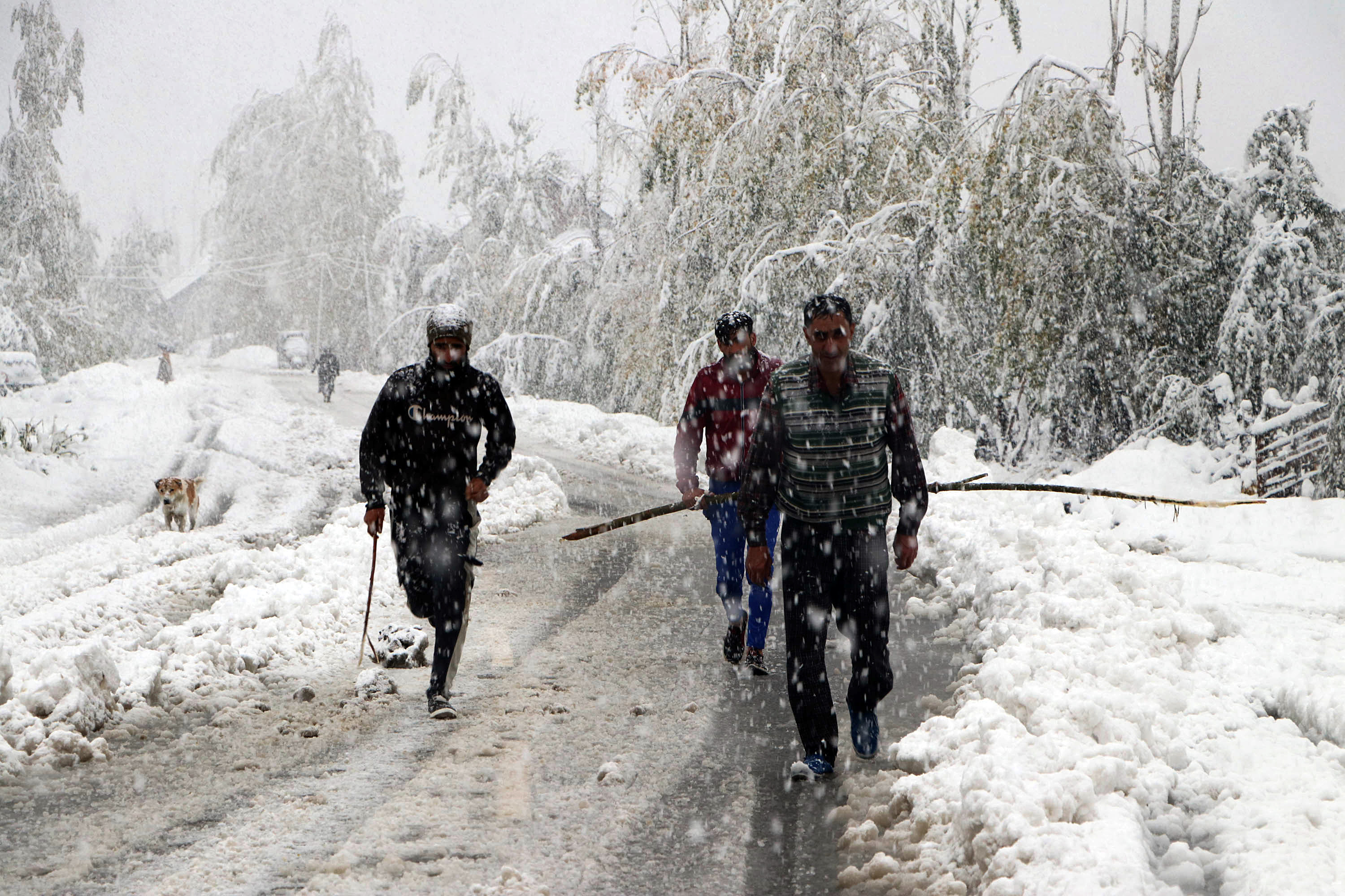 People walk through a road during the snowfall