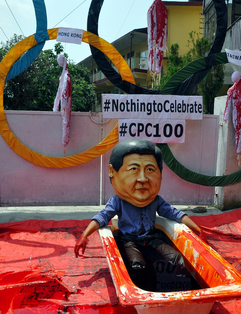 An exile Tibetan activist wearing a mask of Chinese President Xi Jinping sits in a tub filled with red fluid like blood during a protest
