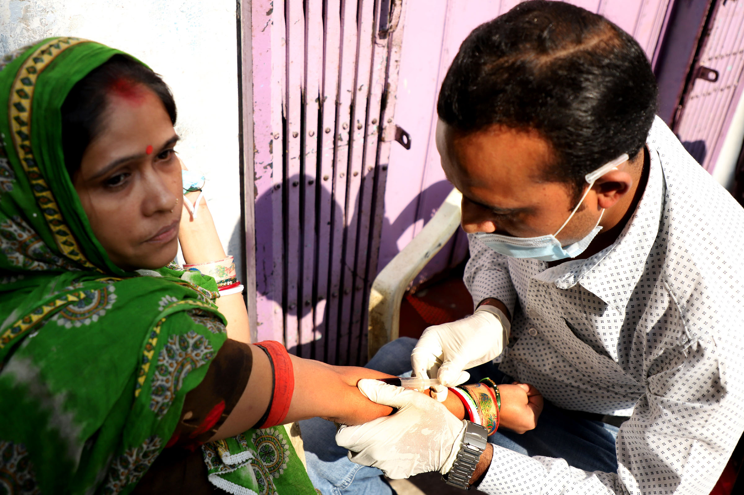 A healthcare worker collects the blood sample of a woman for the Zika virus testing