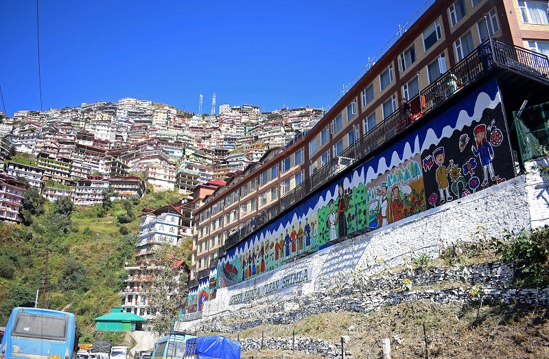 A wall decorated and made by disposed of bottle caps, with the message Green Shimla Clean Shimla to prevent an environment