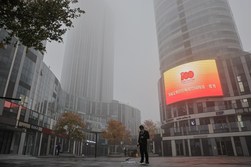 A man stands near a propaganda display of the Chinese Communist Party (CCP) in the Sanlitun shopping district, in Beijing