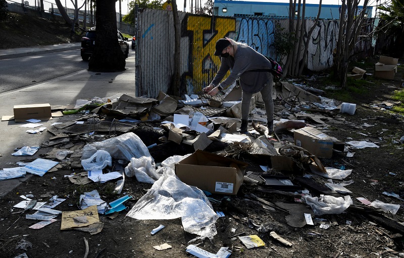 TV reporter takes photos of the mess created with the remains of items stolen from passing freight trains, in Los Angeles