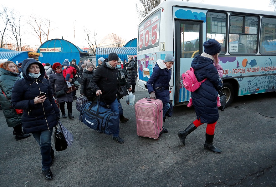 People walk to board a bus during the evacuation of local residents to Russia, in Donetsk