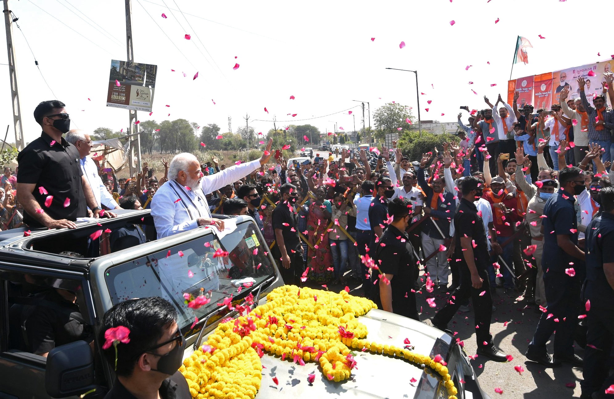 Narendra Modi waves to the people on the way from Gandhinagar to Raksha Shakti University