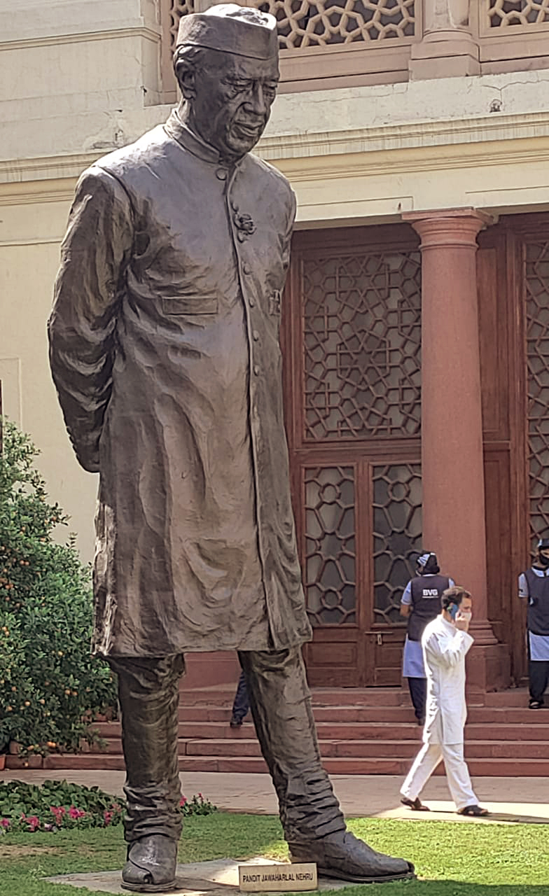 Rahul Gandhi speaks on a phone call as he walks past the statue of Jawaharlal Nehru