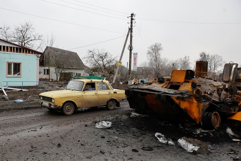 Local resident drives past a destroyed Russian armoured personal carrier in the village of Nova Basan