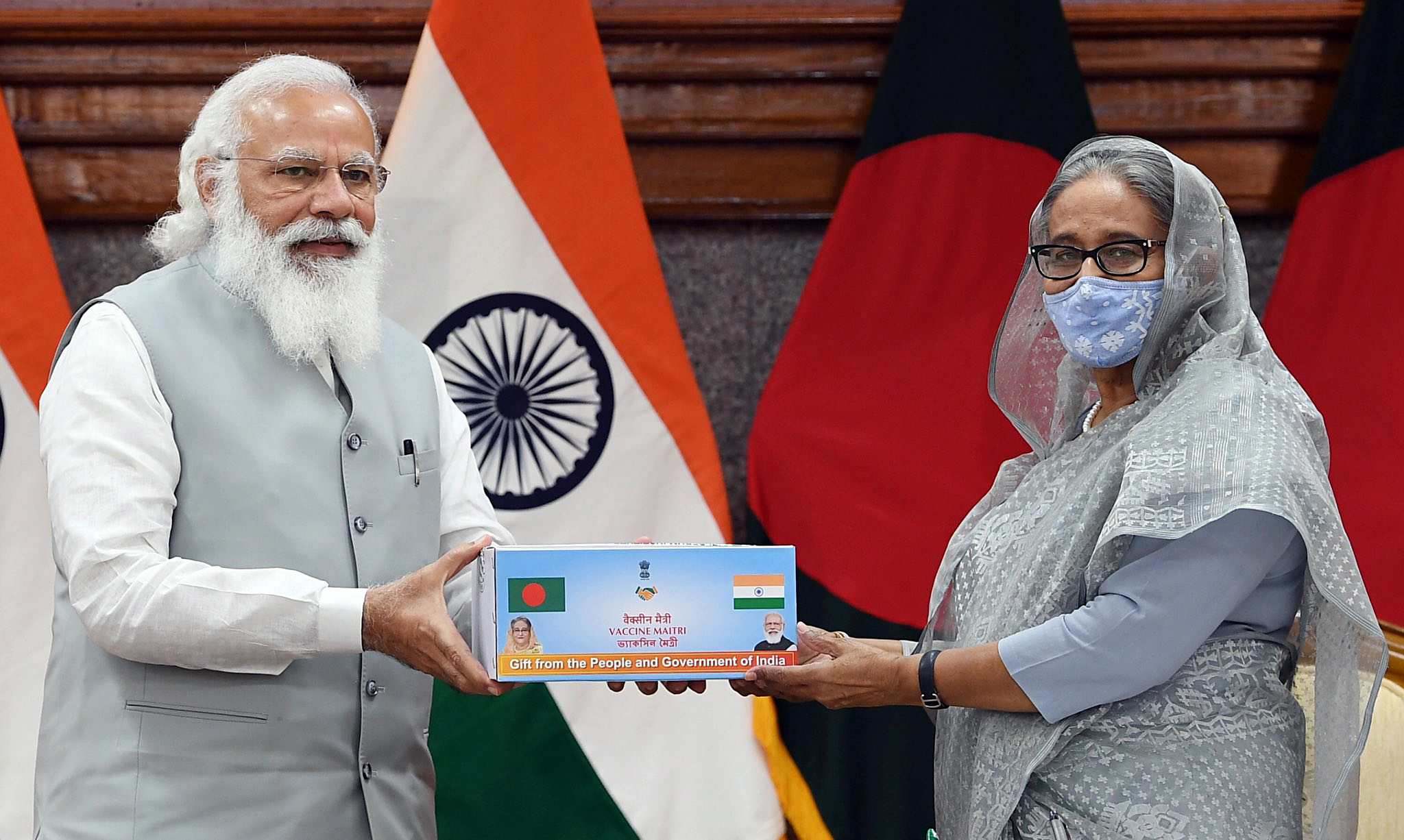 Prime Minister Narendra Modi hands over a representational item to Bangladesh PM Sheikh Hasina as a symbol of India's gift of 1.2 million COVID vaccine doses