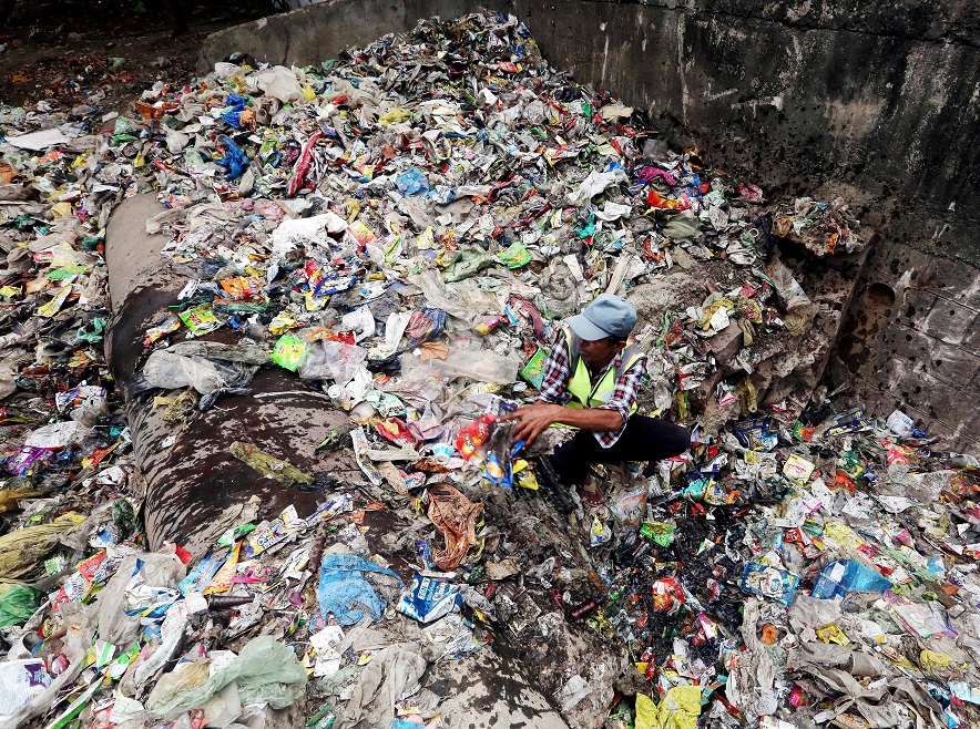 BMC worker cleans the garbage dumped near the banks of Lower Lake on the eve of World Environment Day