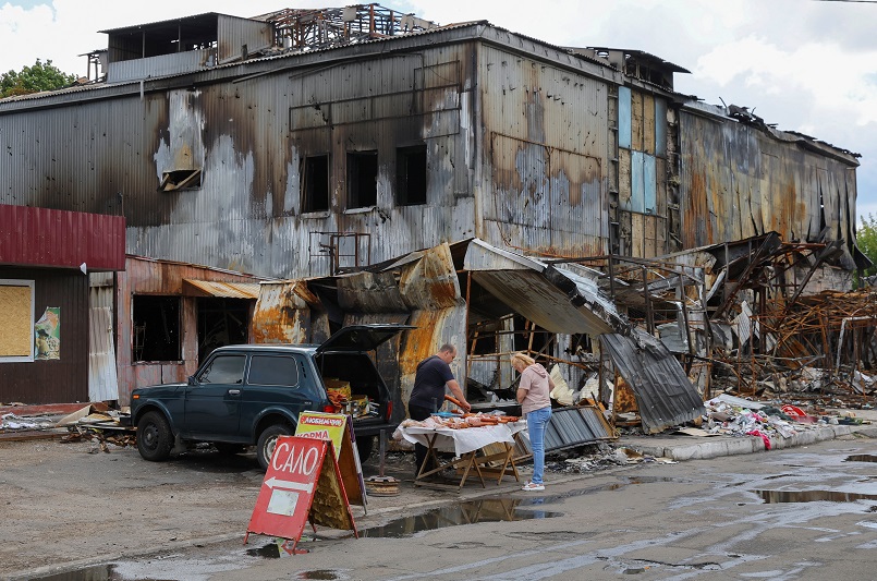 A vendor sells meat products in front of a destroyed market in Donetsk