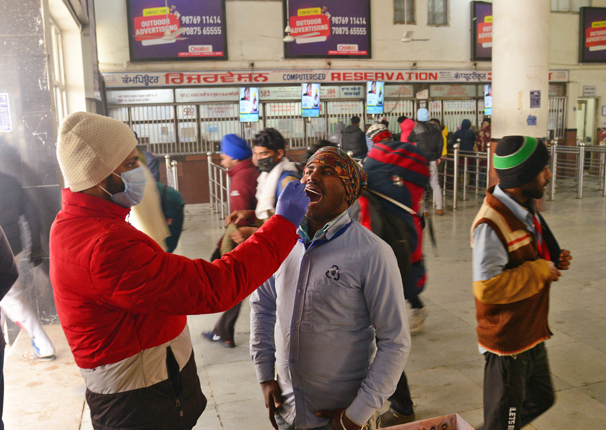 A Healthcare worker collects an oral swab sample from a passenger