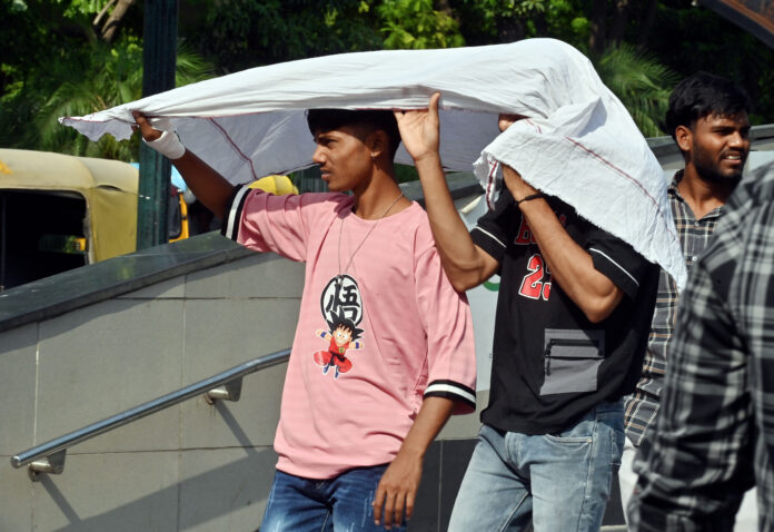 People cover their heads with a cloth to protect themselves from the sun on a hot summer day