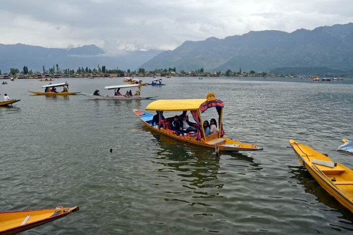 Tourists enjoying Shikara ride on the waters of Dal Lake on a summer afternoon