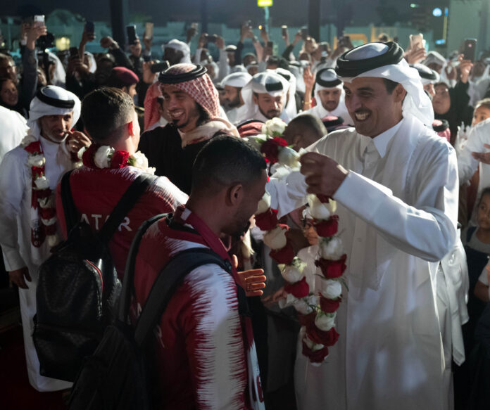 Emir Sheikh Tamim bin Hamad Al Thani gives flower necklace to Qatar players as they celebrate winning the Asian Cup