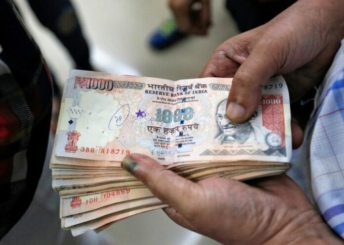 A customer waits to deposit 1000 Indian rupee banknotes in a cash deposit machine at bank in Mumbai