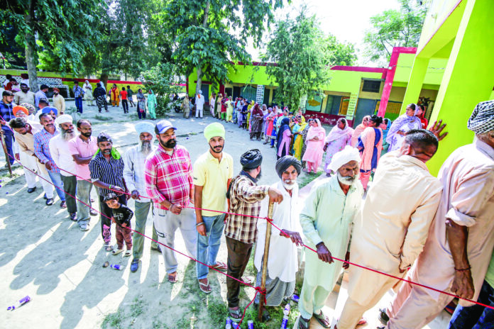 Villagers stand in queues to cast their votes at a polling station for the Gram Panchayat elections at Meharban Pura village, near Amritsar on Tuesday. ANI