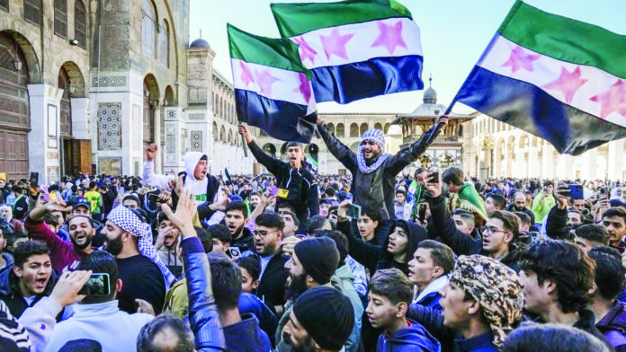 Syrians chant slogans and wave the new Syrian flag as they gather for Friday prayers at the Umayyad mosque in Damascus, Syria, on Friday. Syrians chant slogans and wave the new Syrian flag as they gather for Friday prayers at the Umayyad mosque in Damascus, Syria, on Friday.