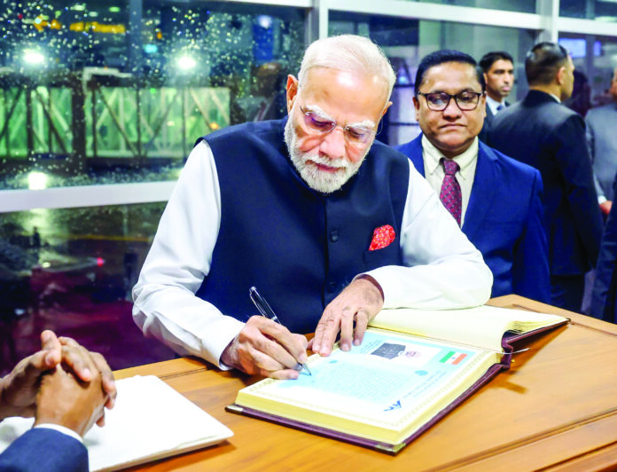 Prime Minister Narendra Modi signs a book on his arrival, in Colombo on Friday. ANI